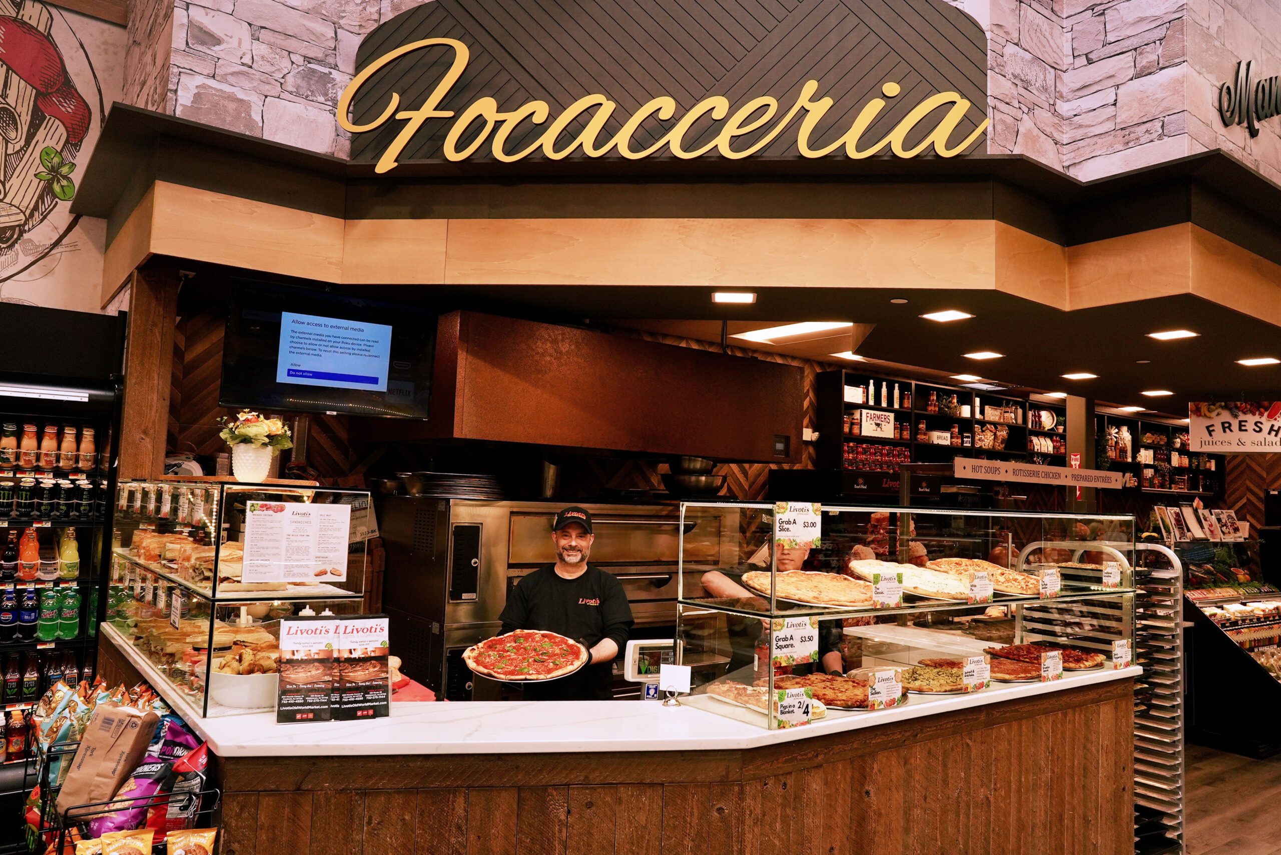 Man standing at a counter with a freshly made pizza at Livoti's Old World Market in Freehold, NJ